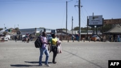 FILE - A man and a woman cross the road on July 28, 2018 at the Beitbridge border post, near Musina, used by many Zimbabweans as a way to get back into Zimbabwe from South Africa. 