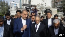 Iranian Foreign Minister Hossein Amir-Abdollahian, center left, walks with his Syrian counterpart Faisal Mekdad, center right, and Iran's Ambassador to Syria Hossein Akbari, center, during a visit to the site destroyed by airstrikes, in Damascus on April 8, 2024. 