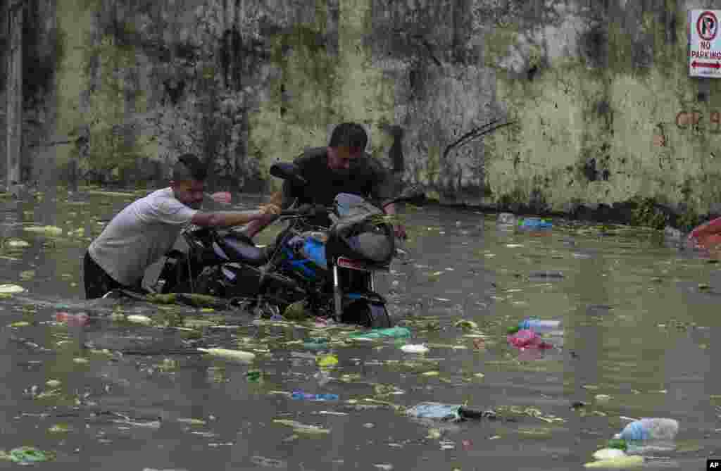 Two men push a motorcycle through flood waters after heavy monsoon rains flooded a vegetable market in Kathmandu, Nepal.