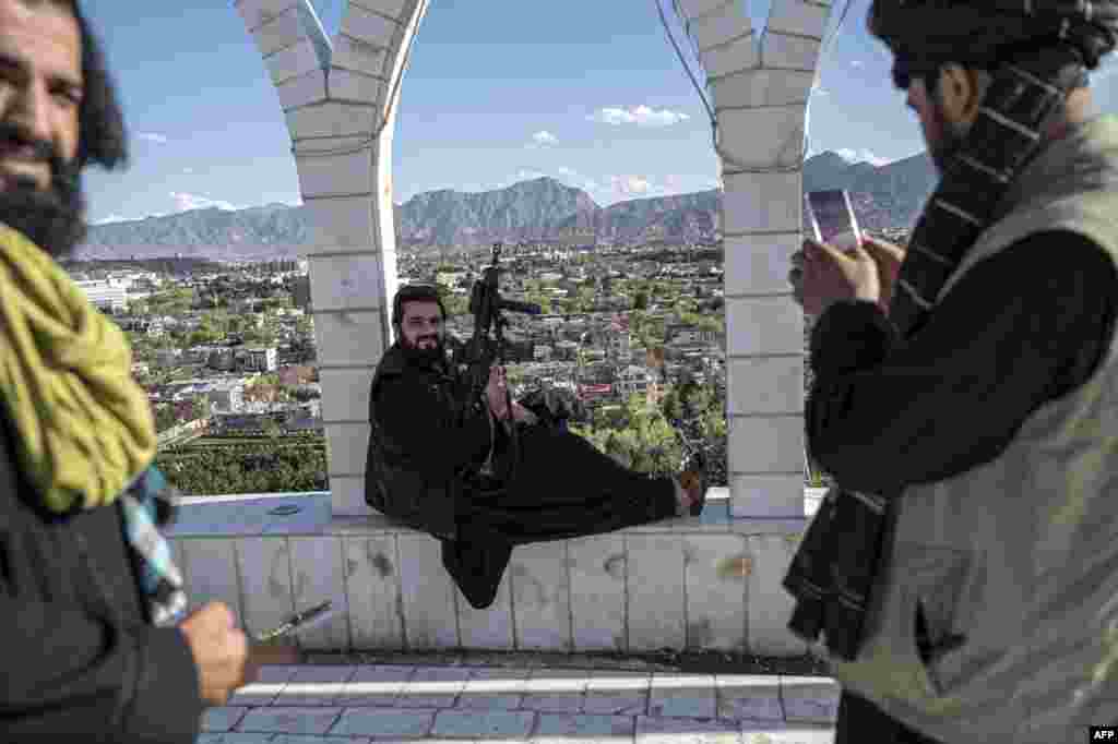 A Taliban security personnel take pictures of his colleague using a mobile phone at the Wazir Akbar Khan hilltop overlooking Kabul.