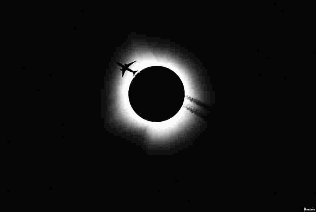An airplane passes near the total solar eclipse during the Hoosier Cosmic Celebration at Memorial Stadium in Bloomington, Indiana, April 8, 2024.