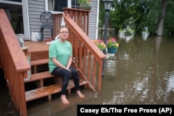 Rachel Morsching sits on the flooded porch of her father Dean Roemhildt's home in Waterville., Minnesota, June 25, 2024.