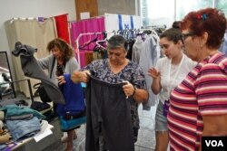 Una voluntaria ayuda a varias mujeres evacuadas a escoger ropa donada.