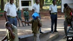 Street currency dealers cover their faces while making a court appearance at the magistrates courts in Harare, Zimbabwe, Thursday, April 25, 2024. 