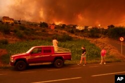 Local residents try to reach their houses in Benijos village as fire advances in La Orotava in Tenerife, Canary Islands, Spain, Aug. 19, 2023.