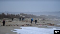 移民木船在斯特卡托迪庫特羅鎮（Steccato di Cutro）附近的海灘上，碎裂的藍色木頭像火柴棍一樣散落在沙灘上。