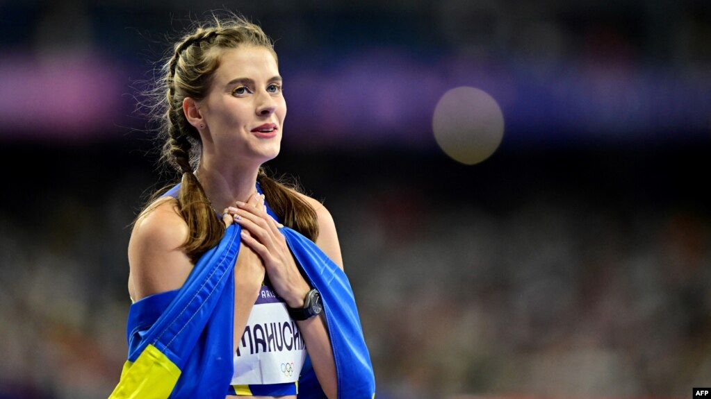 Gold medallist Ukraine's Yaroslava Mahuchikh celebrates, wrapped in a Ukrainian flag, after competing in the women's high jump final at the Paris 2024 Olympic Games at Stade de France in Saint-Denis, north of Paris, Aug. 4, 2024.