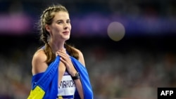 Gold medallist Ukraine's Yaroslava Mahuchikh celebrates, wrapped in a Ukrainian flag, after competing in the women's high jump final at the Paris 2024 Olympic Games at Stade de France in Saint-Denis, north of Paris, Aug. 4, 2024.