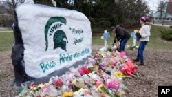 FILE - Mourners leave flowers at The Rock on the grounds of Michigan State University in East Lansing, Mich., Feb. 15, 2023. 