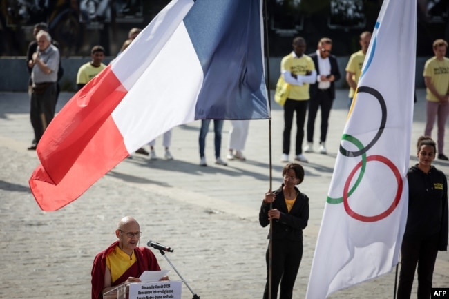 Co-president of the Union Bouddhiste de France Lama Jigme Thrinle Gyatso (L) addresses the audience as he takes part in an interreligious meeting on the parvis of Notre Dame de Paris cathedral in Paris on Aug. 4, 2024.