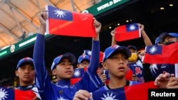 FILE - Baseball players hold the Taiwanese flag while waiting for the match between Taiwan and Panama in the 2023 World Baseball Classic game in Taichung, Taiwan March 8, 2023. 