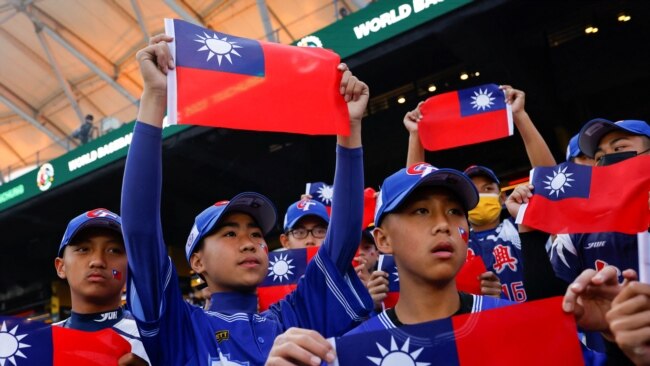 FILE - Baseball players hold the Taiwanese flag while waiting for the match between Taiwan and Panama in the 2023 World Baseball Classic game in Taichung, Taiwan March 8, 2023.