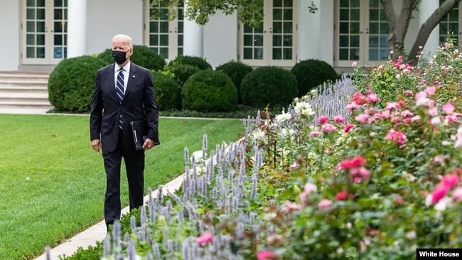 President Joe Biden walks through the White House Rose Garden.