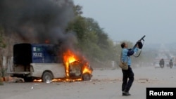 A police officer fires a tear gas can as supporters of former Pakistani Prime Minister Imran Khan clash with police outside a Federal Judicial Complex in Islamabad, March 18, 2023.