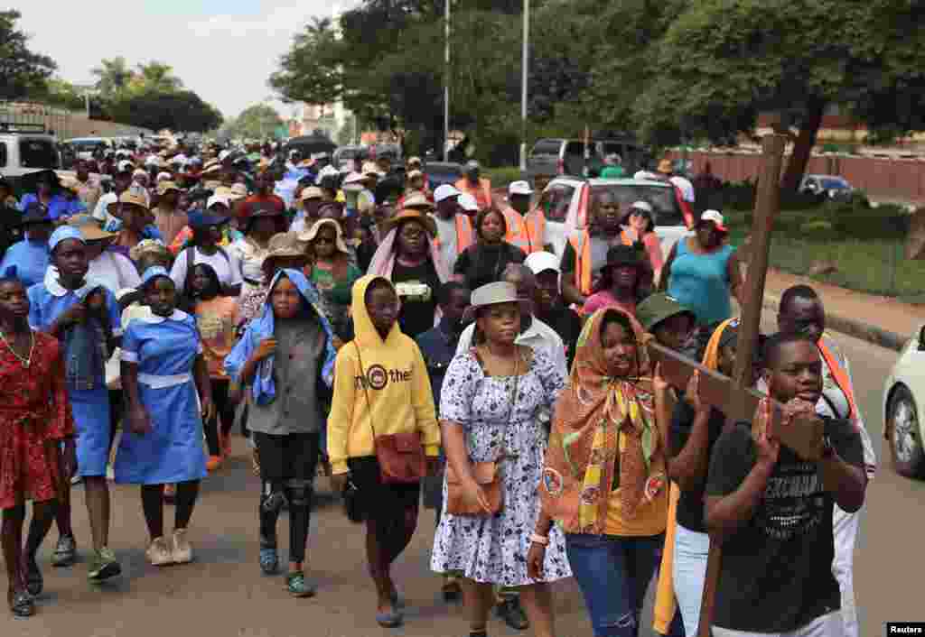 Los católicos romanos llevan una cruz mientras avanzan por una calle mientras conmemoran el Viernes Santo durante el inicio de la Pascua en Harare, Zimbabwe.