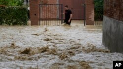 A man walks in a flooded street in the village of Castel Bolognese, Italy, May 17, 2023. 