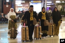 FILE - Para jemaah yang hendak menunaikan umrah, membawa koper dan barang bawaannya di Bandara Internasional Soekarno-Hatta, Tangerang, 27 Februari 2020. (AP/Tatan Syuflana)