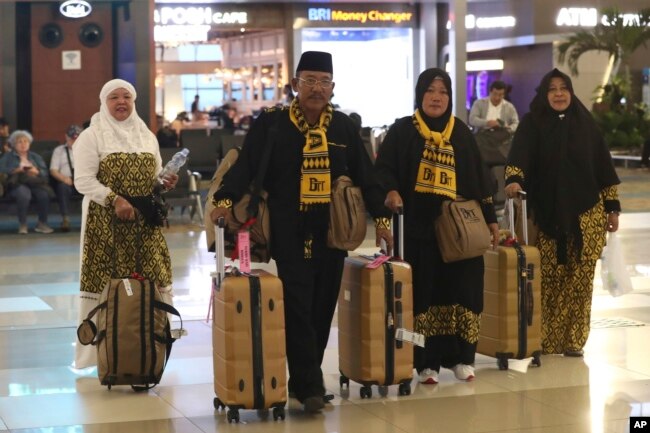 FILE - Para jemaah yang hendak menunaikan umrah, membawa koper dan barang bawaannya di Bandara Internasional Soekarno-Hatta, Tangerang, 27 Februari 2020. (AP/Tatan Syuflana)