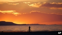 A man on a bike photographs the sunset at the Great Salt Lake on June 13, 2024, near Salt Lake City.
