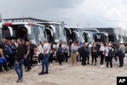 Supporters of Serbian president Aleksandar Vucic stand next to buses in Belgrade, Serbia, May 26, 2023.