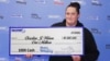 En esta fotografía publicada por la Comisión de Lotería del Estado de Massachusetts, Christine Wilson de Attleborough, sostiene un cheque por 1 millón de dólares el 1 de mayo de 2024. 