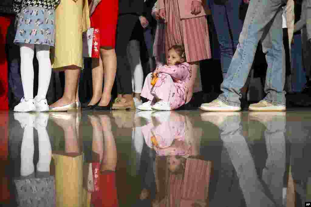 An Orthodox girl sits next to her family member during an easter service in the Orthodox church in Sarajevo, Bosnia, May 5, 2024.