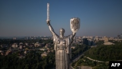 Steeplejacks are installing the coat of arms of Ukraine on the shield of the 102-metre Motherland Monument in Kyiv on August 6, 2023. (Photo by Roman PILIPEY / AFP)