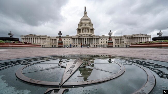 FILE - The U.S. Capitol Dome is reflected in a rain puddle on the compass star on the east side of the building, Sept. 24, 2023.
