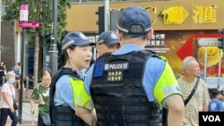 有身穿戰術背心的軍裝警員在背部貼上標語。(美國之音照片)
