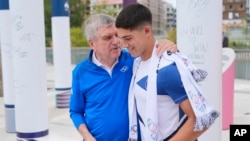 International Olympic Committee President Thomas Bach hugs Israeli soccer player Niv Yehoshua during the inauguration of the Olympic Truce Wall in the Olympic Village at the 2024 Summer Olympics, July 22, 2024, in Paris.