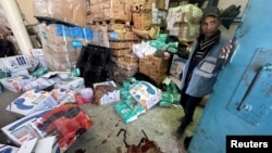 A Palestinian worker stands next to boxes of aid stained with blood, at an UNRWA aid distribution center following an Israeli strike, as the conflict between Israel and Hamas continues, in Rafah, in the southern Gaza Strip, March 13, 2024.