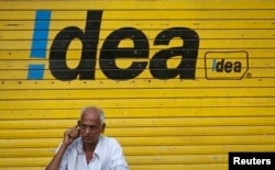 資料照：一名印度男子在孟買街頭的印度手機通訊商Idea的標識廣告前打手機。 （2014年4月28日）
