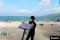 FILE - A waiter works in a beach with a few Western tourists, which is usually full of Chinese tourists, amid fear of coronavirus in Phuket, Thailand, March 10, 2020.