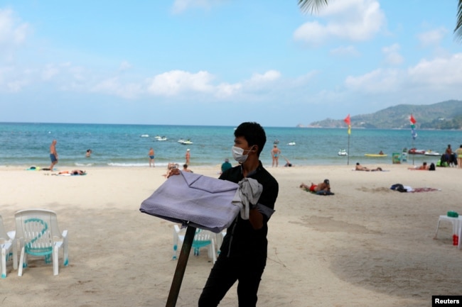 FILE - A waiter works in a beach with a few Western tourists, which is usually full of Chinese tourists, amid fear of coronavirus in Phuket, Thailand, March 10, 2020.