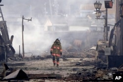 A firefighter walks through the rubble and wreckage of a burnt-out marketplace following earthquake in Wajima, Ishikawa prefecture, Japan Tuesday, Jan. 2, 2024. (Kyodo News via AP)