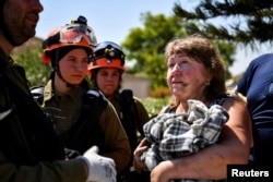 A woman speaks to Israeli officials after saving her dog from her home that was damaged by rockets fired from Lebanon, amid cross-border hostilities between Hezbollah and Israel, in Katzrin in the Israeli-occupied Golan Heights, Aug. t 21, 2024.