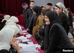 Voters receive their ballots at a polling station during the presidential election in the village of Akhmat-Yurt in the Chechen Republic, Russia, March 15, 2024.