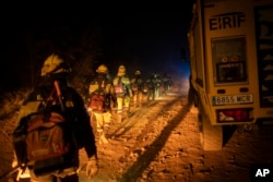 Emergency crews and firefighters walk to the fire advancing through the forest near the town of El Rosario in Tenerife, Canary Islands, Spain, Aug. 18, 2023.