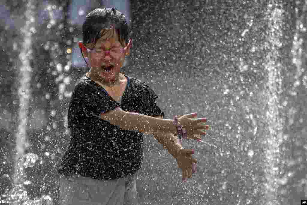 A girl reacts as she plays in a fountain at a shopping mall in Beijing. Officials issued a rare red alert for hot weather in parts of China&#39;s capital, the highest level of warning, as the temperature was expected to climb to around 40 degrees Celsius.