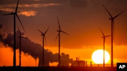 FILE: Steam rises from the coal-fired power plant near wind turbines Niederaussem, Germany, as the sun rises Nov. 2, 2022.