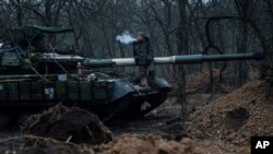 A Ukrainian serviceman smokes a cigarette while standing on top of a tank near Bakhmut, Ukraine, March 8, 2023. 