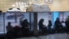 FILE - Immigrants from Venezuela are reflected in a marble wall while taking shelter at the Chicago Police Department's 16th District station on May 1, 2023.