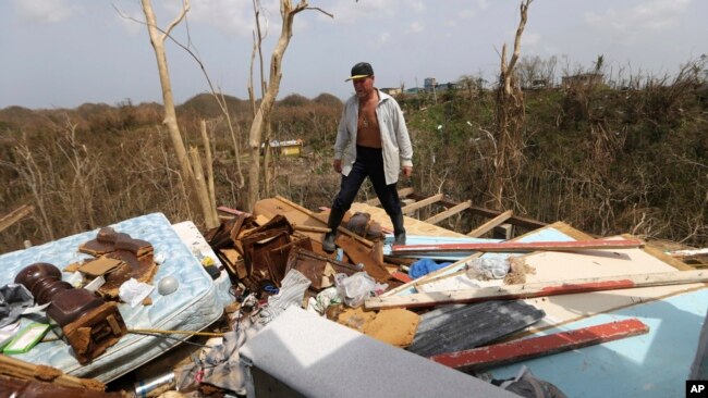 FILE - Jose Trinidad walks on what's left of his home in Montebello, Puerto Rico, in the aftermath of Hurricane Maria, Sept. 26, 2017.