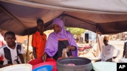 FILE - A woman prepares food in Niamey, Niger, July 29, 2023. The United Nations on Aug. 16, 2023, urged humanitarian exemptions to sanctions and border closures to avert a food-insecurity catastrophe. 