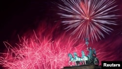 Cahaya kembang api menghiasi patung Quadriga yang berada di atas Gerbang Brandenburg saat perayaan Malam Tahun Baru di Berlin, Jerman, 1 Januari 2024. REUTERS/Annegret Hilse