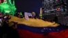 Venezolanos que viven en México y miembros del Comando ConVzla sostienen una bandera venezolana&nbsp;gigante durante una protesta contra los resultados electorales que otorgaron al presidente venezolano Nicolás Maduro un tercer mandato, en el monumento del Ángel de la Independencia en la Ciudad de México.