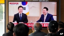 People watch a TV screen showing South Korean President Yoon Suk Yeol, right, meeting with main opposition Democratic Party leader Lee Jae-myung, during a news program at the Seoul Railway Station in Seoul, April 29, 2024. 