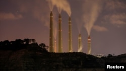 FILE - Smoke and steam billows from the coal-fired power plant owned by Indonesia Power, next to an area for Java 9 and 10 Coal-Fired Steam Power Plant Project in Suralaya, Banten province, Indonesia, July 11, 2020.