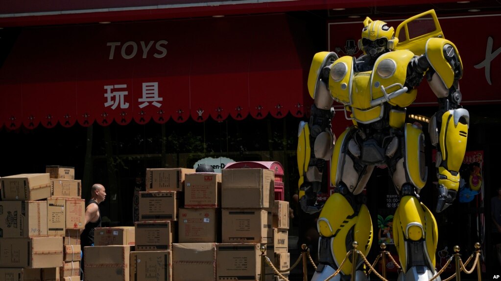 北京一名工人在运送将出口英国著名汉姆利玩具店的大黄蜂玩具。(2023年7月25日)(photo:VOA)