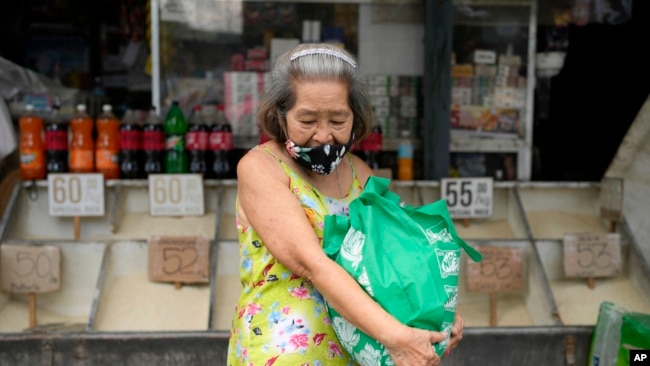 A woman carries a bag of rice from a store in Quezon city, Philippines, on Monday, Aug. 14, 2023. Countries worldwide are scrambling to secure rice after a partial ban on exports by India cut supplies by roughly a fifth.